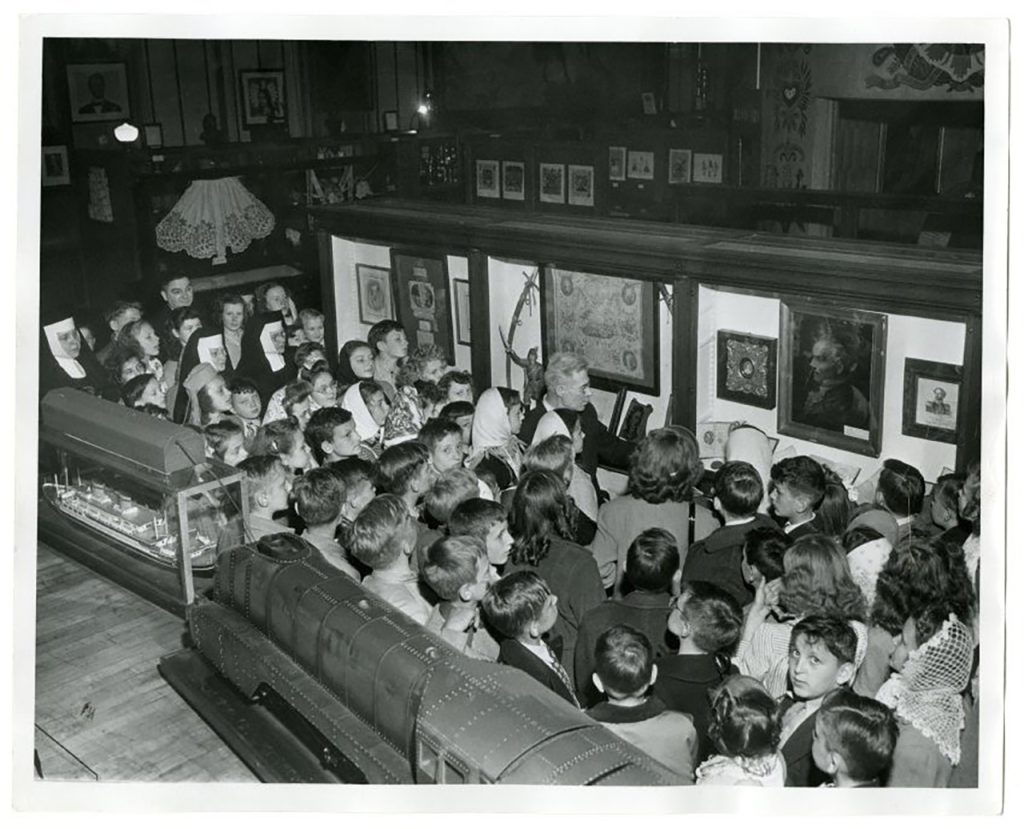 Visit from St James School, 1947. In the middle M. Haiman, Curator of the Museum, explains artifacts on display in the Great Hall of Exhibits.